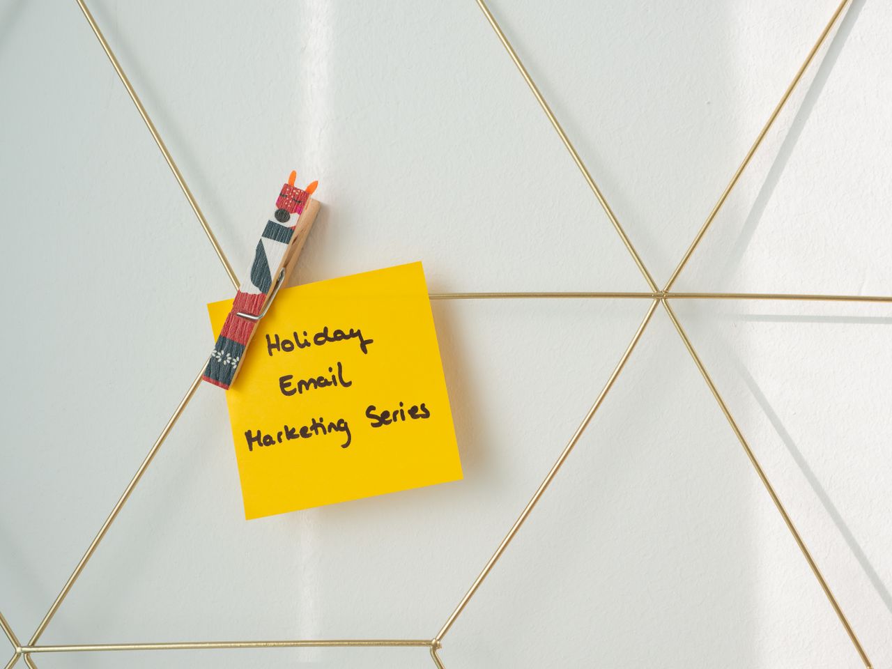 Post-it jaune vif avec un message de marketing par e-mail pour les fêtes, fixé sur un mur en filaire.